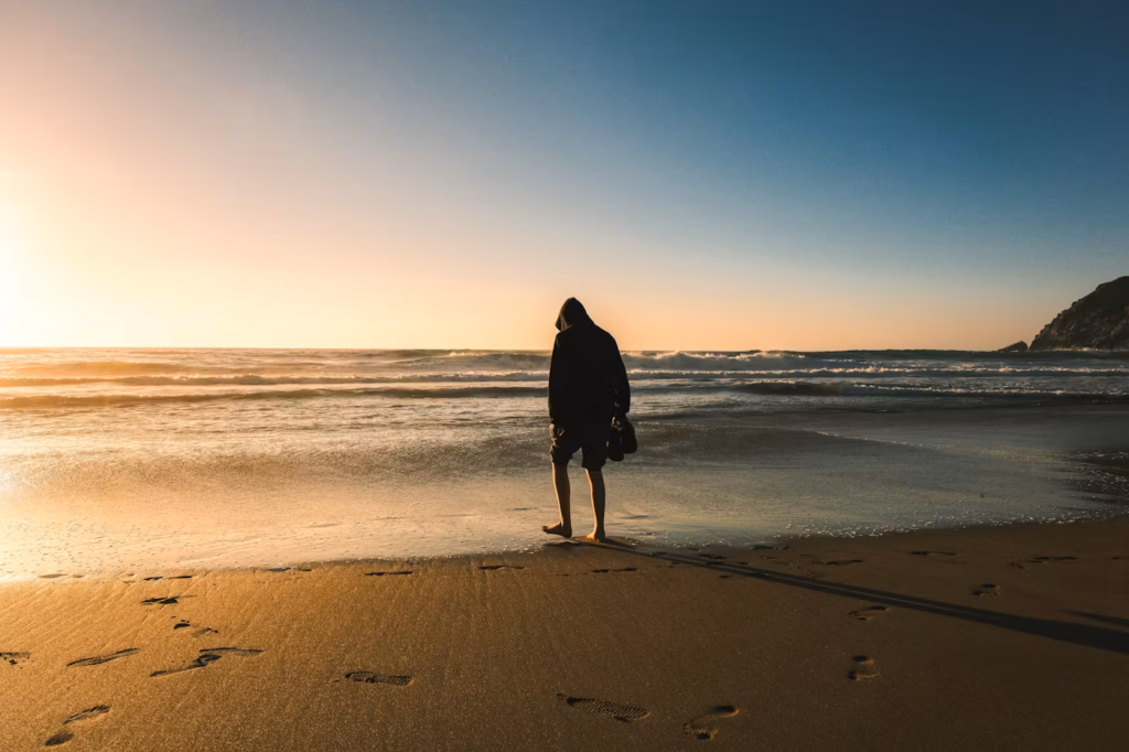 Person walking along a calm beach representing hope and reaching out for help