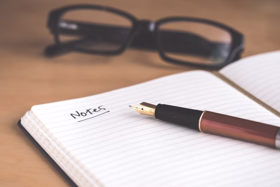 Person journaling with a phone nearby during a daily reflection